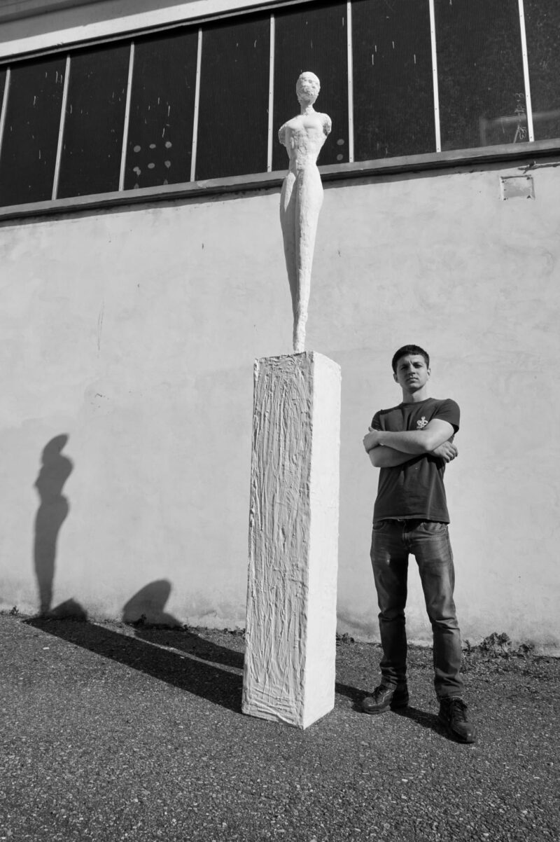 Alessandro Giove che posa accanto alla sua scultura ètoile